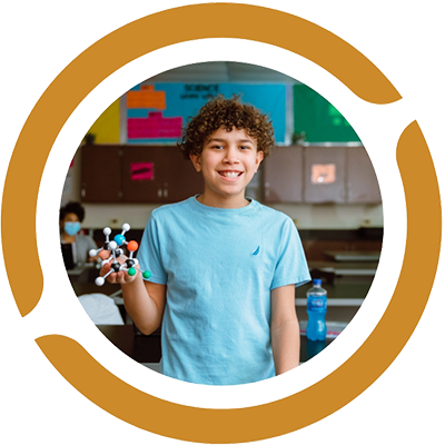 young boy in a classroom holding a molecule example