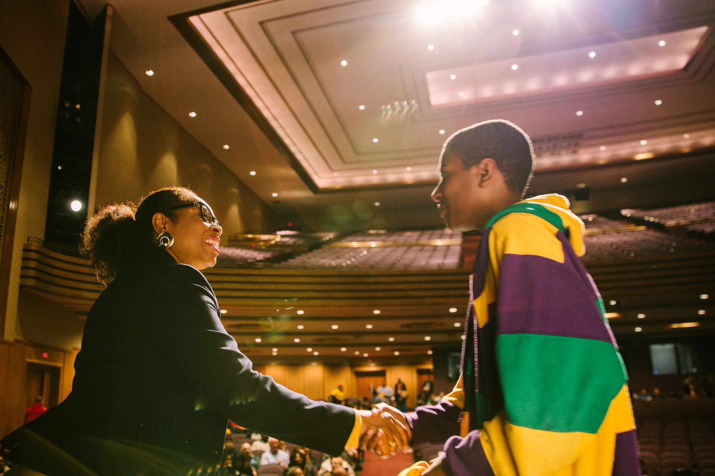 student shaking hands with adult